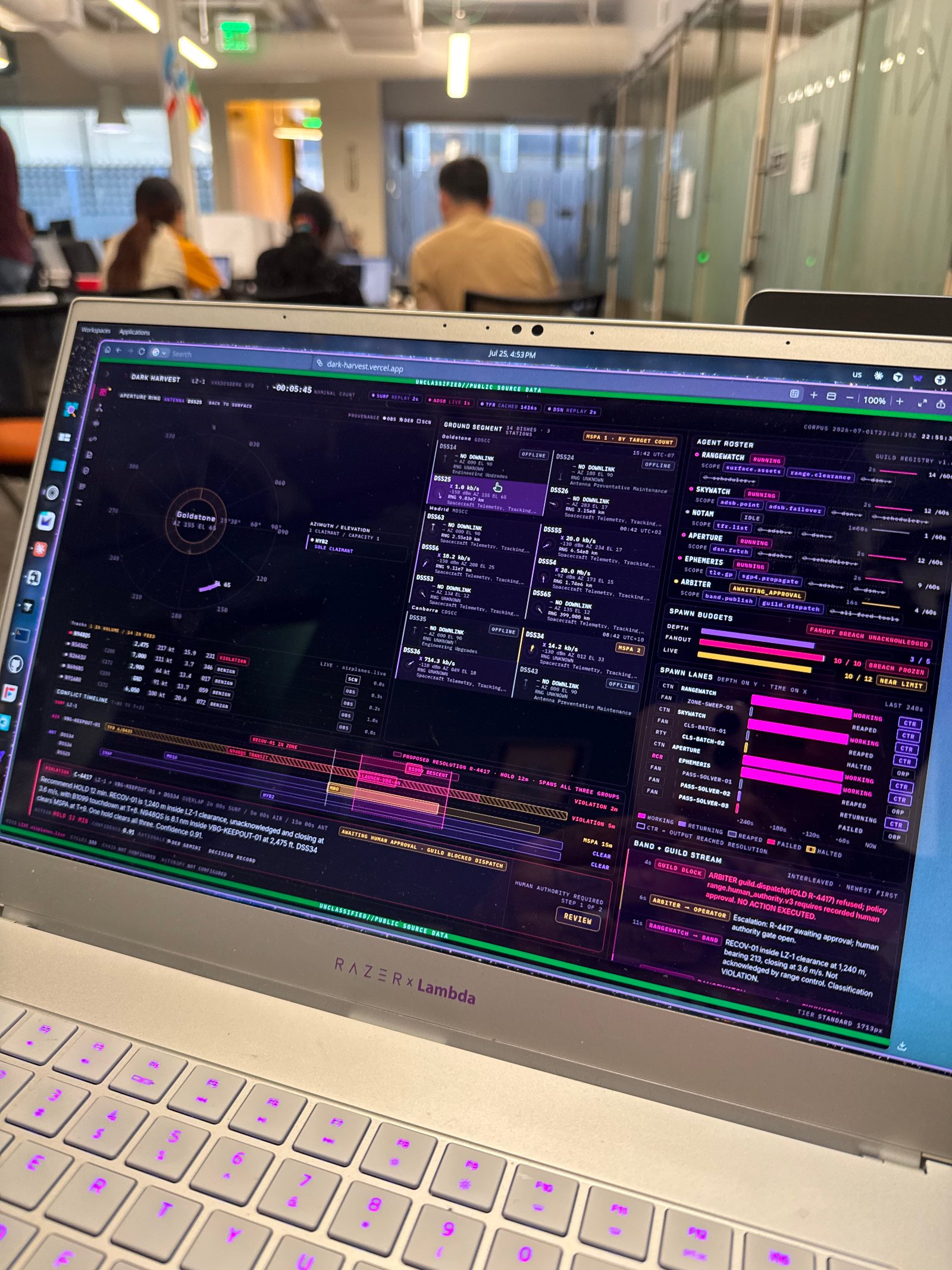 The Dark Harvest operator console running on a laptop on the hackathon floor in Palo Alto, the conflict timeline and agent rail visible on screen.